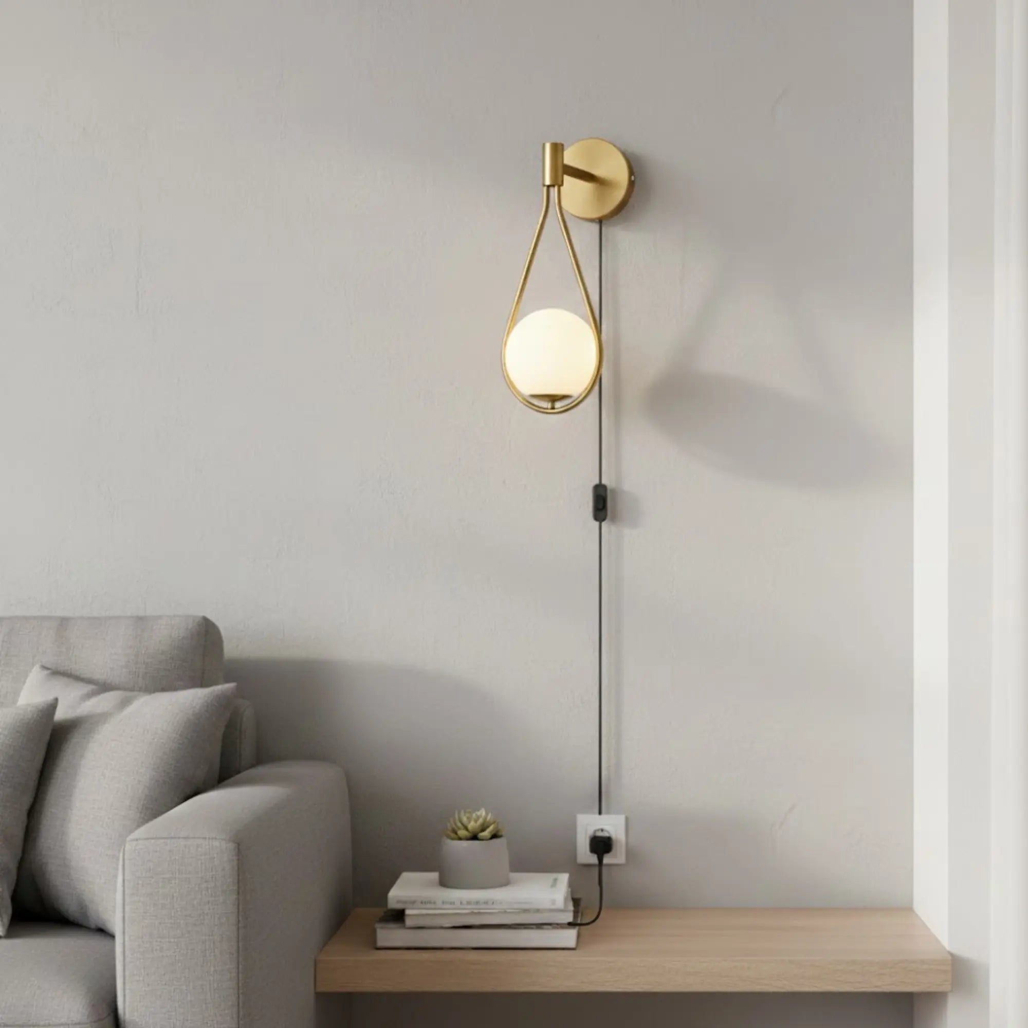 Applique murale dorée à bras arrondi avec globe lumineux et interrupteur intégré.